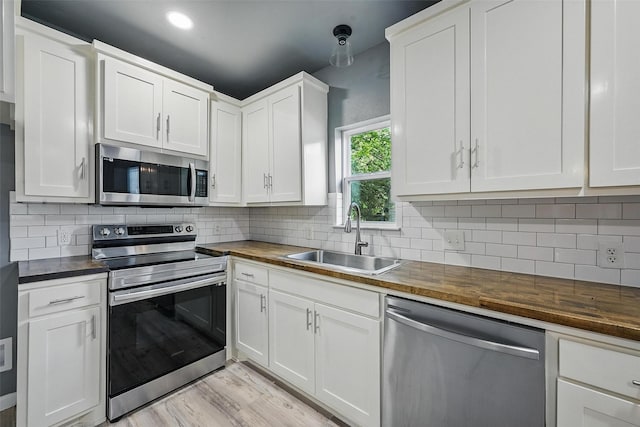 906 S Willow St, Sherman, TX 75090 - kitchen featuring appliances with stainless steel finishes, butcher block countertops, white cabinetry, light wood-type flooring, and backsplash