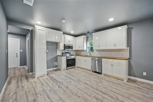 906 S Willow St, Sherman, TX 75090 - kitchen with appliances with stainless steel finishes, light wood-style floors, backsplash, white cabinetry, and wood counters