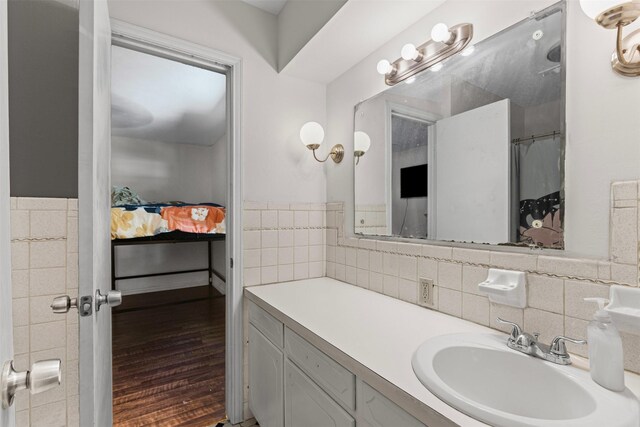 103 Auburn St, Waxahachie, TX 75165 - bathroom featuring connected bathroom, wood finished floors, vanity, a wainscoted wall, and tile walls