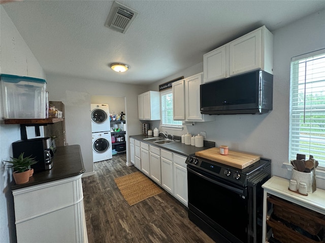 706 Jefferson Ave, Cisco, TX 76437 - kitchen featuring black appliances, stacked washing machine and dryer, a sink, white cabinetry, and dark wood-style floors