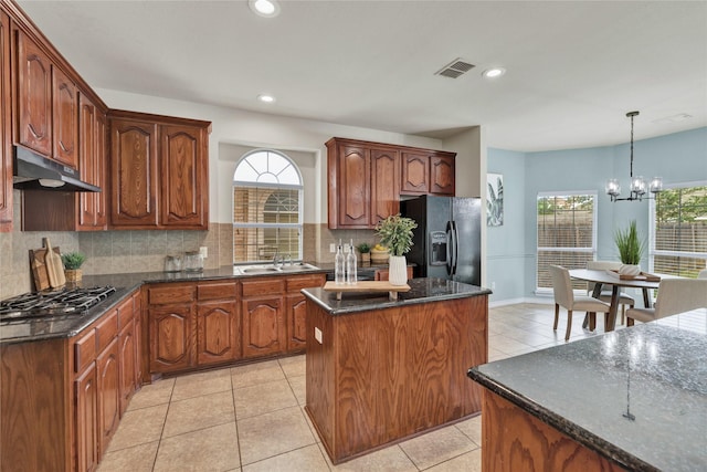 8620 Thistle Ridge Ter, Fort Worth, TX 76123 - kitchen with black fridge with ice dispenser, under cabinet range hood, gas stovetop, a center island, and decorative backsplash