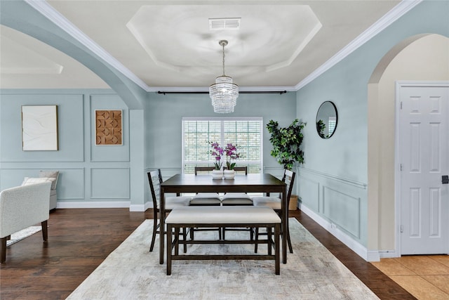 8620 Thistle Ridge Ter, Fort Worth, TX 76123 - dining space with a decorative wall, a tray ceiling, arched walkways, wood finished floors, and crown molding