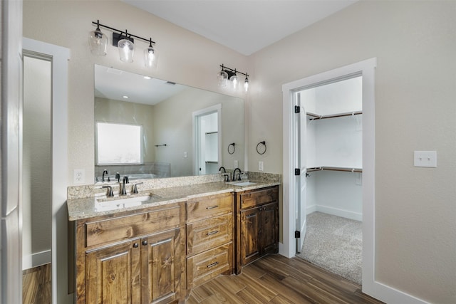 105 Carls Ct, Boyd, TX 76023 - full bathroom with wood finished floors, double vanity, a walk in closet, and baseboards