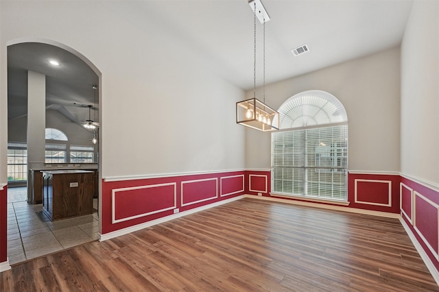 2110 Pecan Ridge Dr, Forney, TX 75126 - empty room with wood finished floors, a wainscoted wall, arched walkways, ceiling fan, and a high ceiling