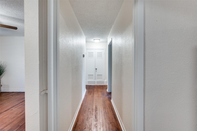7612 Oxley Dr, Richland Hills, TX 76118 - hallway featuring a textured ceiling, wood finished floors, a textured wall, and baseboards