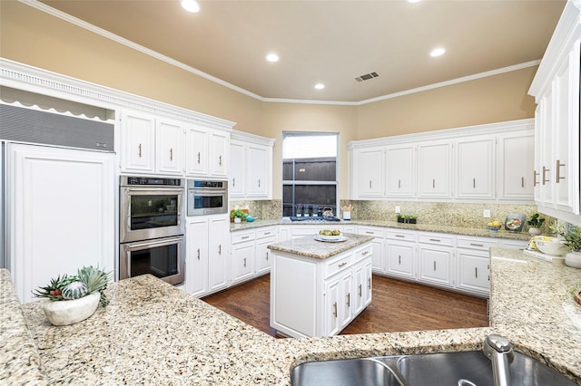 5115 Oak Tree Cir, Dallas, TX 75287 - kitchen featuring stainless steel double oven, white cabinets, backsplash, dark wood finished floors, and light stone countertops