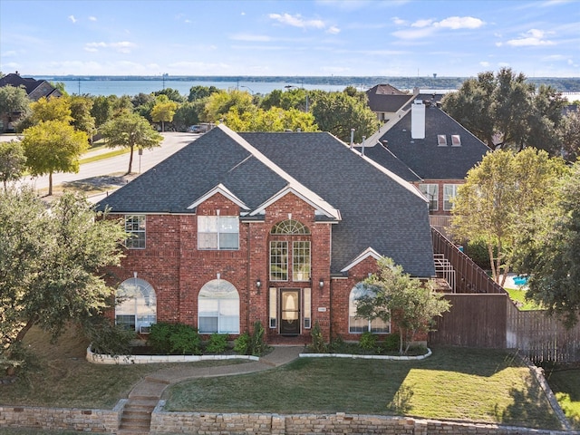 1705 Bayhill Dr, Rockwall, TX 75087 - traditional home with roof with shingles, brick siding, a chimney, and a water view