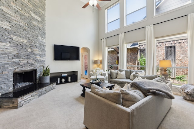 4104 Navarro Way, Frisco, TX 75034 - carpeted living room with a towering ceiling, arched walkways, a ceiling fan, and a fireplace