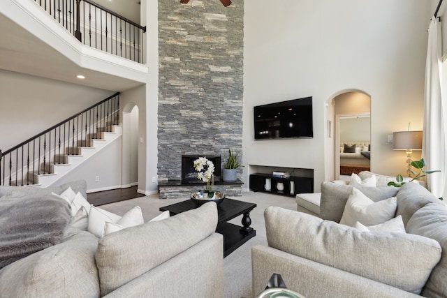 4104 Navarro Way, Frisco, TX 75034 - living room featuring arched walkways, a towering ceiling, baseboards, stairs, and a fireplace