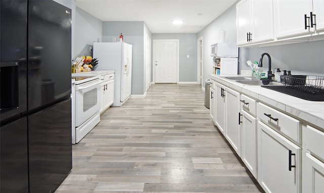 2421 Langston St, Fort Worth, TX 76105 - kitchen with white appliances, a sink, white cabinets, light wood finished floors, and baseboards