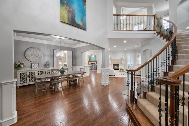7000 Shalimar Ct, Colleyville, TX 76034 - entryway featuring wood finished floors, a towering ceiling, ornamental molding, a glass covered fireplace, and stairs