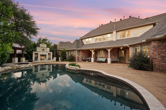 7000 Shalimar Ct, Colleyville, TX 76034 - pool at dusk with a patio, an outdoor living space with a fireplace, and a pool with connected hot tub