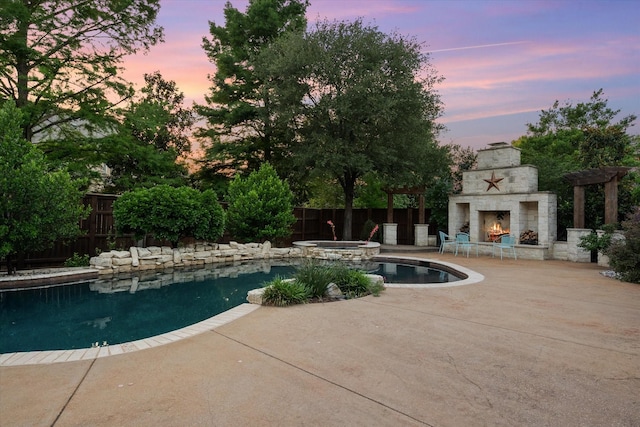7000 Shalimar Ct, Colleyville, TX 76034 - pool at dusk featuring an outdoor stone fireplace, a patio, and a pool with connected hot tub