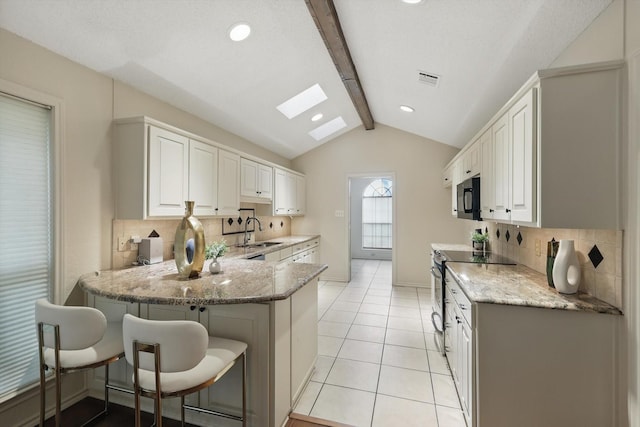 2420 Cross Timbers Trl, Arlington, TX 76006 - kitchen with black microwave, a sink, stainless steel range with electric cooktop, decorative backsplash, and a peninsula