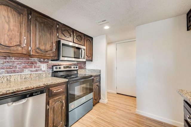 1822 Highbrook Ct, Garland, TX 75044 - kitchen with appliances with stainless steel finishes, baseboards, a textured ceiling, light wood-style flooring, and dark brown cabinetry