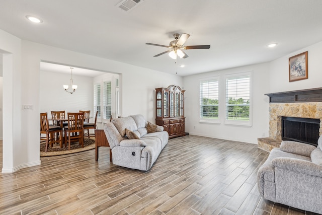 2410 Blackjack Oak Rd, Oak Ridge, TX 75161 - living area with light wood-style floors, ceiling fan, a stone fireplace, a chandelier, and baseboards