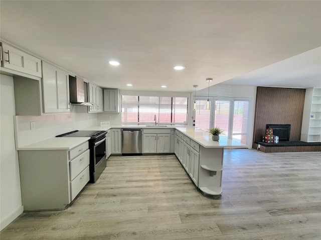 3402 Jones Dr, Rowlett, TX 75088 - kitchen featuring appliances with stainless steel finishes, wall chimney range hood, a peninsula, a sink, and light wood-style flooring