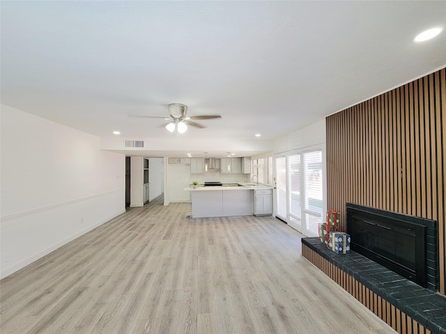 3402 Jones Dr, Rowlett, TX 75088 - unfurnished living room featuring a glass covered fireplace, light wood finished floors, baseboards, a sink, and ceiling fan