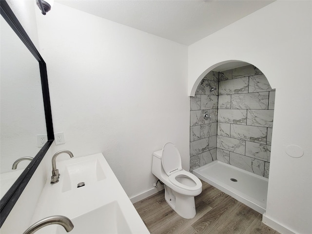 3402 Jones Dr, Rowlett, TX 75088 - full bathroom featuring toilet, tiled shower, wood finished floors, double vanity, and baseboards