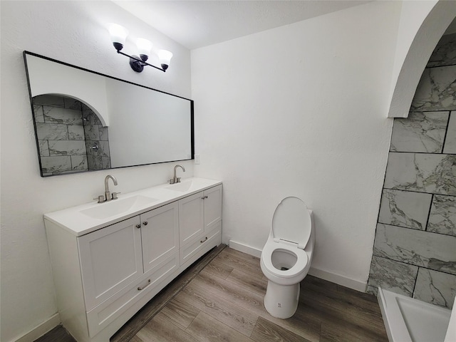 3402 Jones Dr, Rowlett, TX 75088 - full bathroom with double vanity, toilet, baseboards, a shower, and wood finished floors
