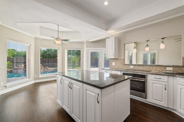 9120 Nob Hill Dr, North Richland Hills, TX 76182 - kitchen with oven, a raised ceiling, a center island, white cabinetry, and decorative backsplash