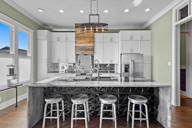 610 W Chestnut St, Denison, TX 75020 - kitchen featuring stainless steel refrigerator with ice dispenser, crown molding, a large island with sink, white cabinets, and tasteful backsplash