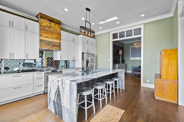 610 W Chestnut St, Denison, TX 75020 - kitchen with crown molding, appliances with stainless steel finishes, tasteful backsplash, a kitchen island with sink, and a breakfast bar area