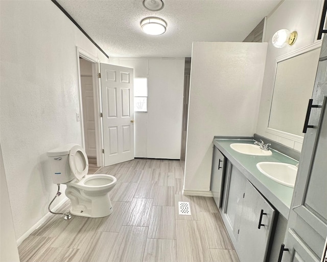 6818 Spring Shower Ct, Krum, TX 76249 - full bathroom with a textured ceiling, toilet, double vanity, baseboards, and a textured wall