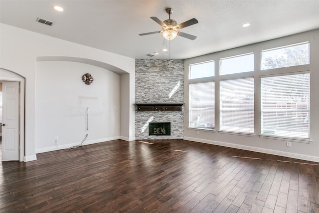 6004 Grand Meadow Ln, Flower Mound, TX 75028 - unfurnished living room with arched walkways, ceiling fan, dark wood-type flooring, a stone fireplace, and recessed lighting