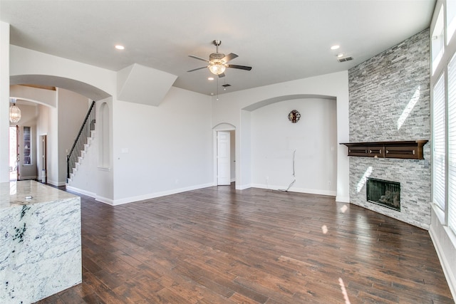 6004 Grand Meadow Ln, Flower Mound, TX 75028 - unfurnished living room featuring a ceiling fan, a fireplace, dark wood-type flooring, arched walkways, and recessed lighting