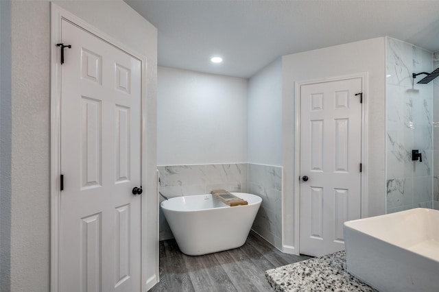 7708 Partridge Dr, Watauga, TX 76148 - full bath featuring wood finished floors, tile walls, a freestanding tub, vanity, and a walk in shower