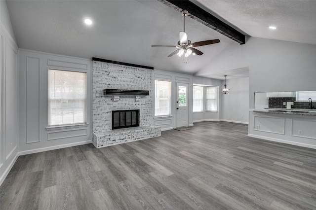 7708 Partridge Dr, Watauga, TX 76148 - unfurnished living room with a ceiling fan, a fireplace, wood finished floors, baseboards, and a chandelier