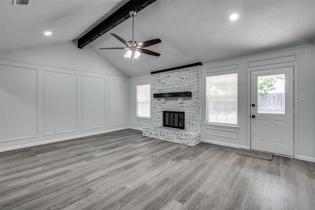 7708 Partridge Dr, Watauga, TX 76148 - unfurnished living room featuring a decorative wall, a ceiling fan, a brick fireplace, and wood finished floors