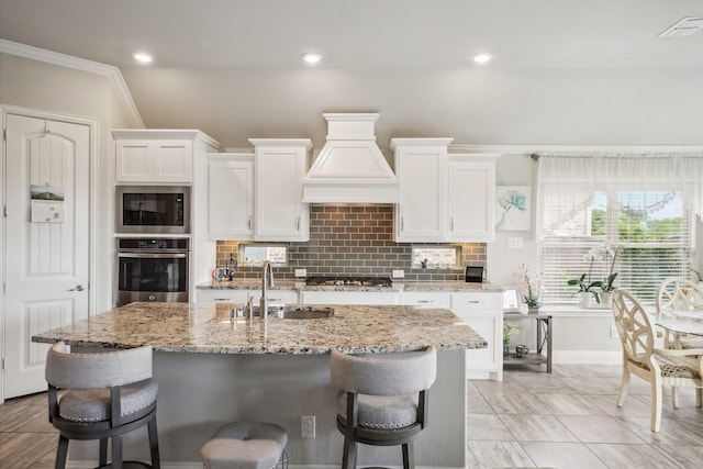 16001 Gladewater Ter, Prosper, TX 75078 - kitchen with appliances with stainless steel finishes, a sink, premium range hood, white cabinetry, and light stone counters
