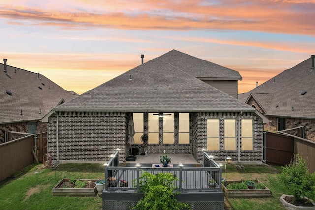 16001 Gladewater Ter, Prosper, TX 75078 - back of property at dusk with a vegetable garden, roof with shingles, and brick siding