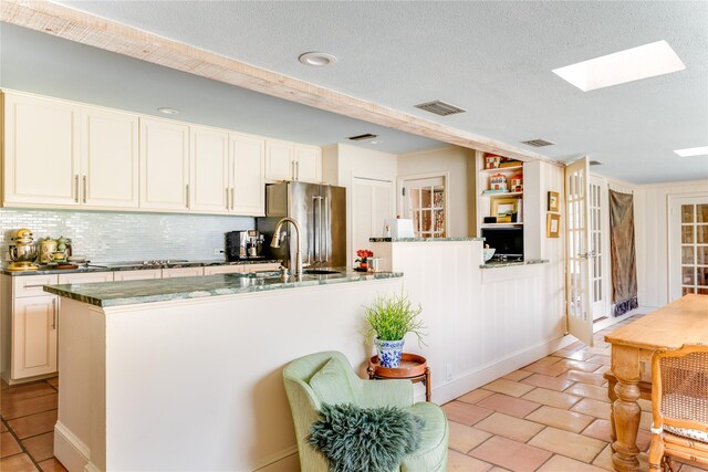 4407 Ridge Rd, Dallas, TX 75229 - kitchen with high end refrigerator, decorative backsplash, a sink, a skylight, and a textured ceiling
