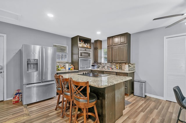 5340 Bourquin St, Dallas, TX 75210 - kitchen featuring stainless steel appliances, light wood-style floors, backsplash, open shelves, and a breakfast bar