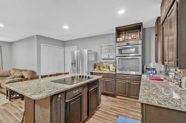 5340 Bourquin St, Dallas, TX 75210 - kitchen with stainless steel fridge, black electric stovetop, a sink, light wood-style flooring, and dark brown cabinets