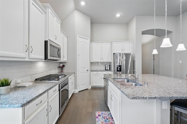7817 Fossil Creek Trl, Mckinney, TX 75071 - kitchen with appliances with stainless steel finishes, a center island with sink, dark wood-style floors, white cabinetry, and backsplash