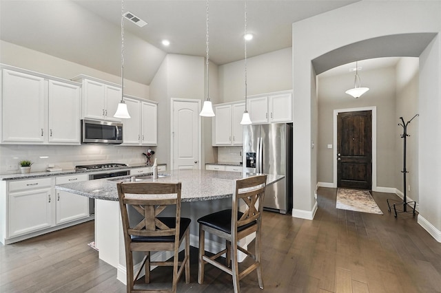 7817 Fossil Creek Trl, Mckinney, TX 75071 - kitchen with appliances with stainless steel finishes, a kitchen island with sink, white cabinets, backsplash, and high vaulted ceiling