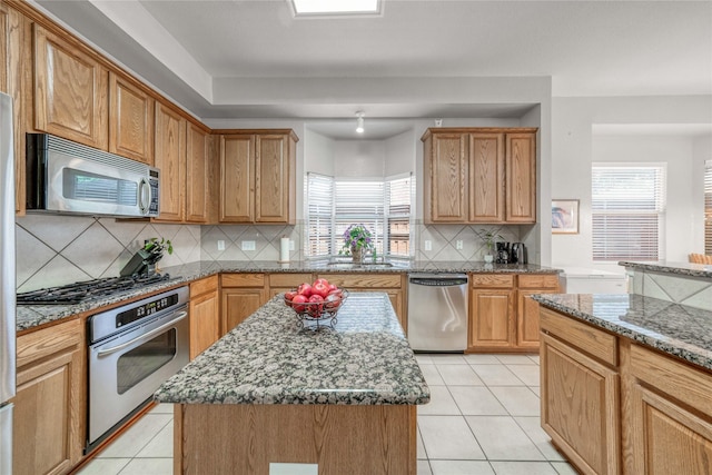 7908 Peacock Ln, Frisco, TX 75035 - kitchen with appliances with stainless steel finishes, light tile patterned floors, backsplash, dark stone countertops, and a kitchen island