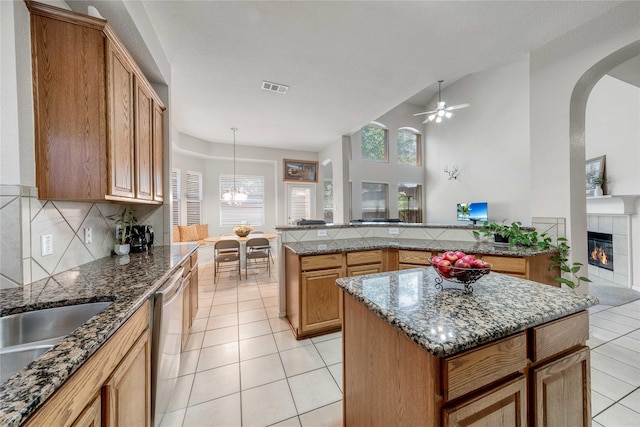 7908 Peacock Ln, Frisco, TX 75035 - kitchen with light tile patterned floors, healthy amount of natural light, a tiled fireplace, a kitchen island, and vaulted ceiling