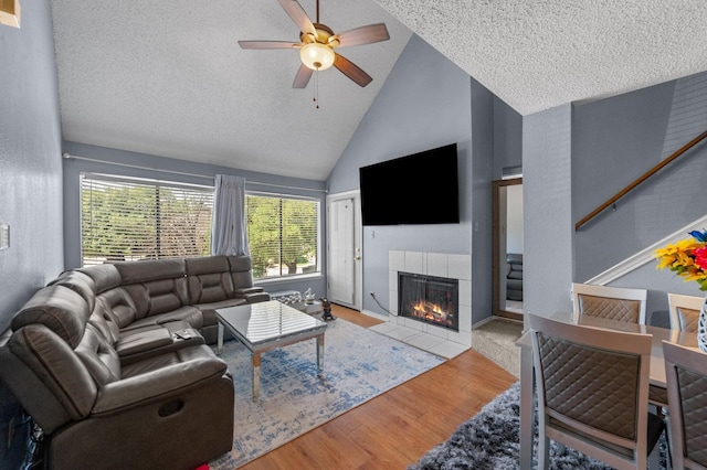 9815 Walnut St Unit 204, Dallas, TX 75243 - living area with a tile fireplace, a ceiling fan, high vaulted ceiling, wood finished floors, and plenty of natural light
