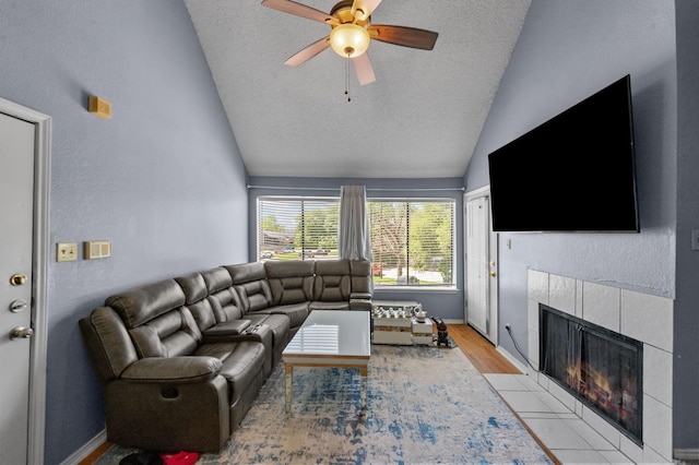 9815 Walnut St Unit 204, Dallas, TX 75243 - living room with vaulted ceiling, a fireplace, a textured ceiling, ceiling fan, and light wood-style flooring