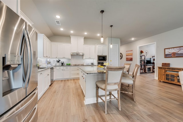 2208 Clancy Dr, Northlake, TX 76247 - kitchen featuring appliances with stainless steel finishes, a breakfast bar area, a kitchen island, backsplash, and light wood-style flooring