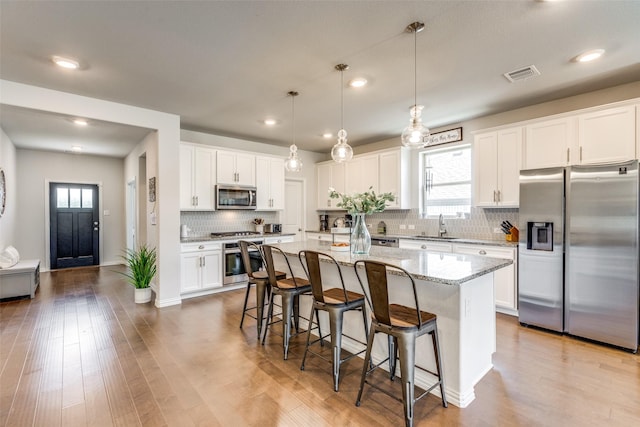 1312 Hutchings Ct, Celina, TX 75009 - kitchen featuring stainless steel appliances, a kitchen breakfast bar, tasteful backsplash, a sink, and healthy amount of natural light