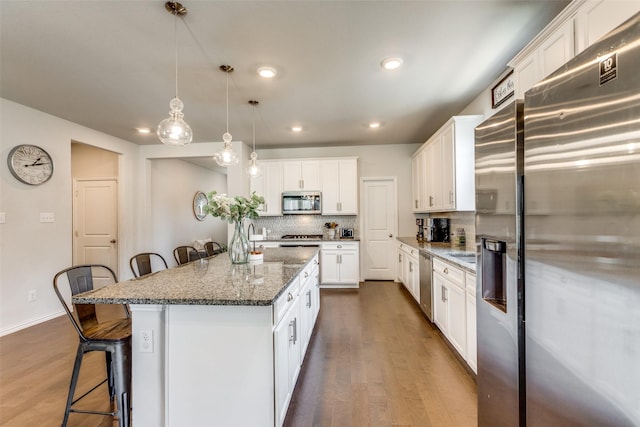 1312 Hutchings Ct, Celina, TX 75009 - kitchen featuring stainless steel appliances, a kitchen breakfast bar, dark wood-type flooring, a kitchen island, and backsplash