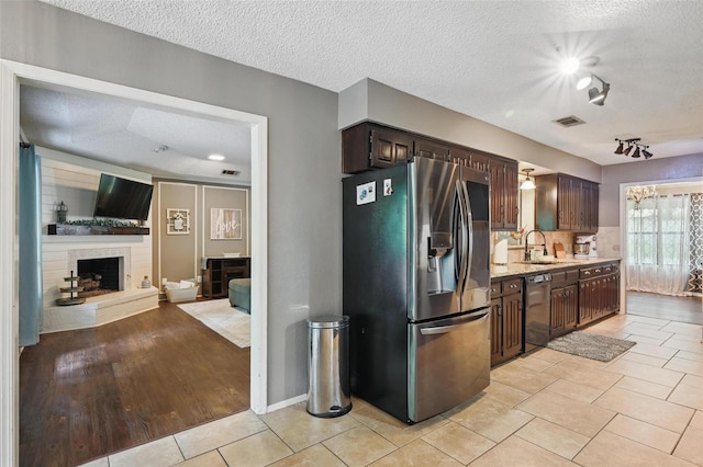 4109 Three Oaks Dr, Arlington, TX 76016 - kitchen with stainless steel refrigerator with ice dispenser, dishwasher, dark brown cabinetry, a sink, and a textured ceiling