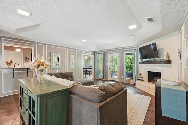 4109 Three Oaks Dr, Arlington, TX 76016 - living room featuring a textured ceiling, dark wood-type flooring, a fireplace with raised hearth, and a decorative wall