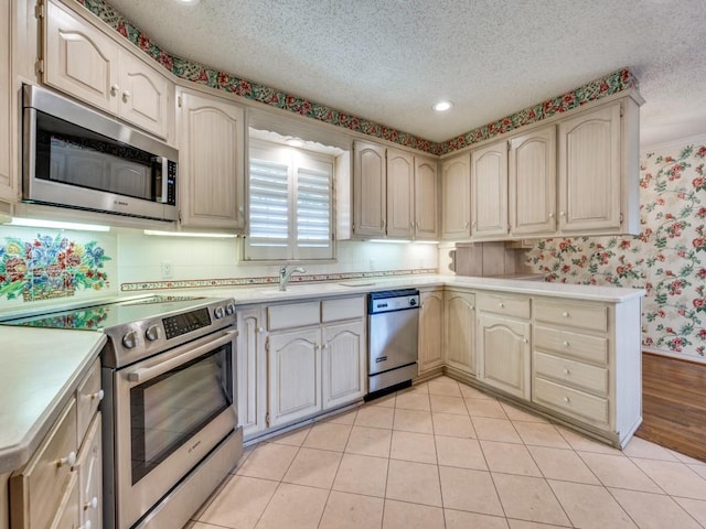 6815 E Mockingbird Ln, Dallas, TX 75214 - kitchen featuring stainless steel appliances, light countertops, wallpapered walls, a textured ceiling, and recessed lighting
